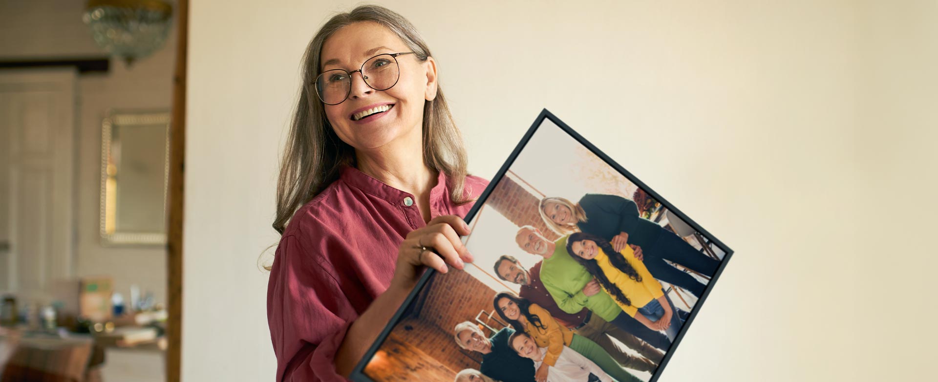 En kvinna håller en inramad tavla med en bild av sin familj