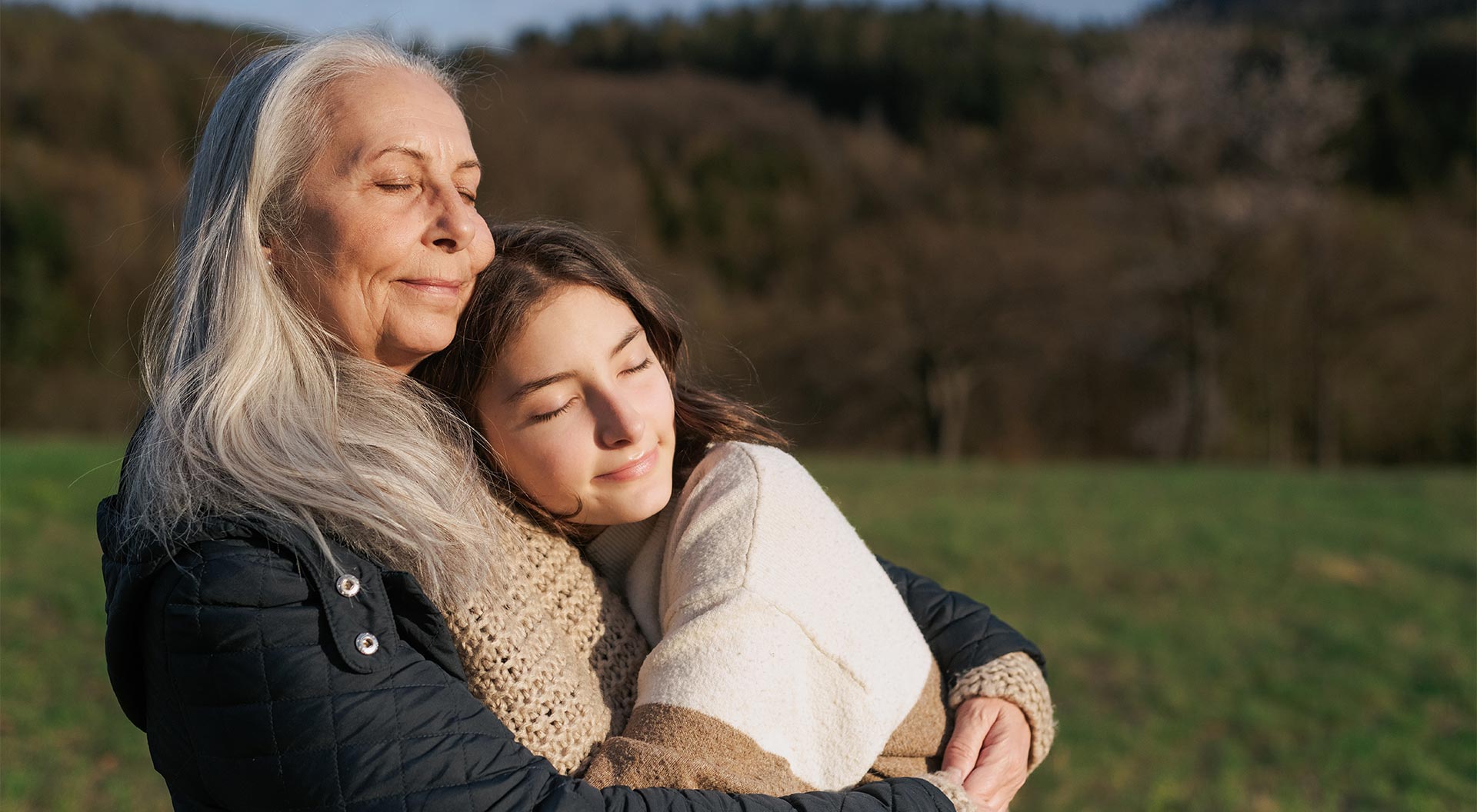 En äldre kvinna kramar en yngre kvinna utomhus